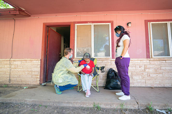 Dr. Ryan Close, left, an Indian Health Services physician, and J.T. Nashio, right, a community health worker, check on Judie Declay, who lives on the Fort Apache Indian Reservation in Arizona, on July 8, 2020.  (Tomás Karmelo Amaya/The New York Times)